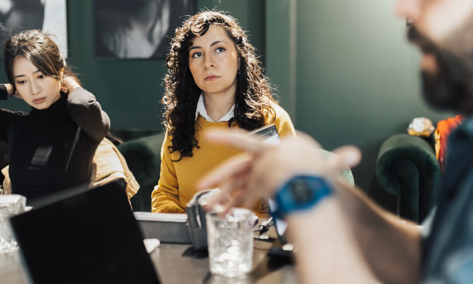 Two colleagues listen closely while a third, in the foreground, gestures as he explains an idea.